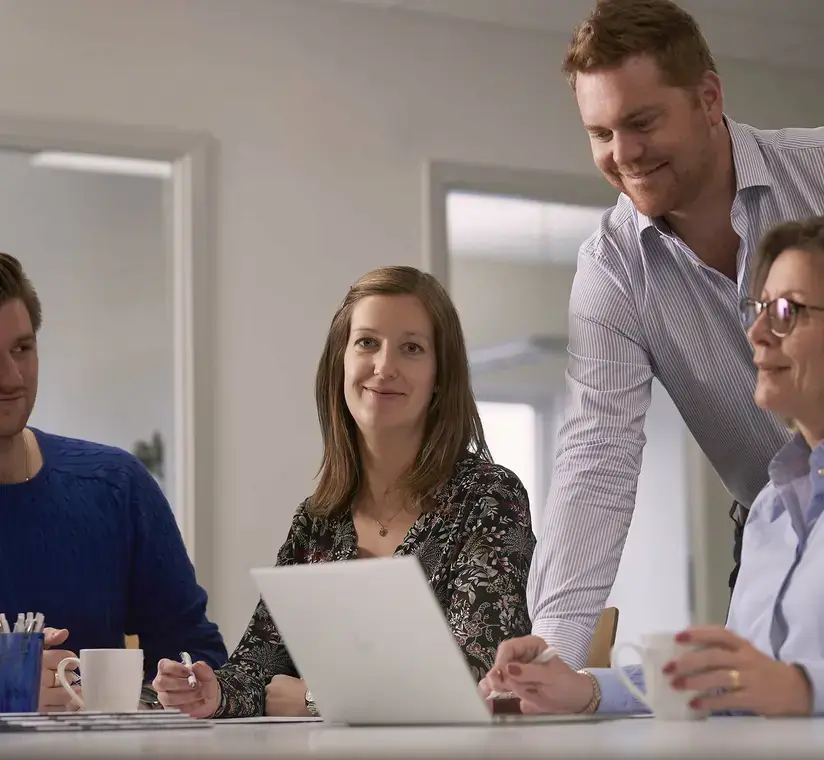 Logimark personal sitter tillsammans vid skrivbord